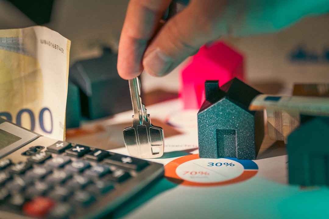 Hand holding house key over miniature home models representing mortgage refinancing decision in Austin