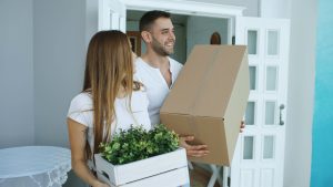 Couple carrying moving boxes into their new Austin home after a mortgage recast lowered their payment