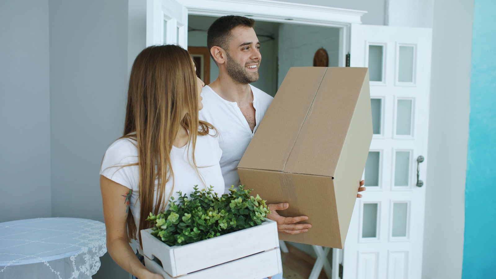 Couple carrying moving boxes into their new Austin home after a mortgage recast lowered their payment