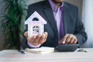 Hand holding a model house, representing saving for a down payment on an Austin home