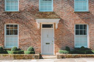 White wooden front door of a brick home, one of two doors Austin buyers weigh when comparing HomeReady vs Conventional 97